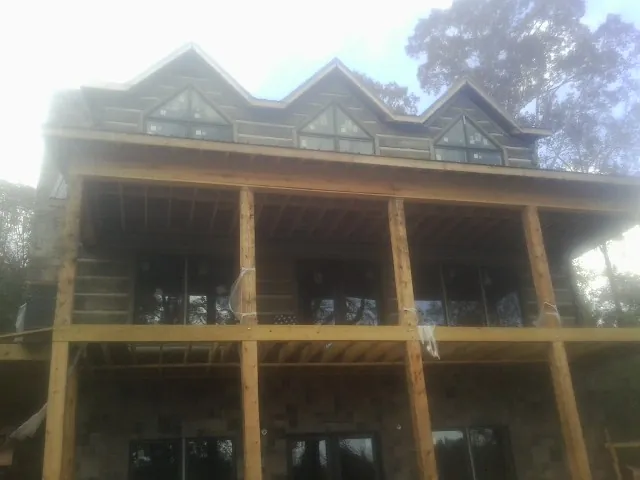 Dormers and porch framing on a large log home under construction — Roof Coating work by our crew in Warm Springs